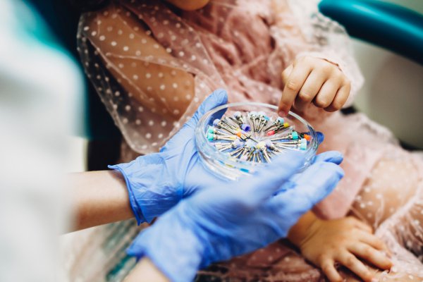 Odontologia humanizada: Abordagem de odontopediatras na adaptação das crianças mãos de uma dentista mostrando equipamentos odontológicos para uma criança