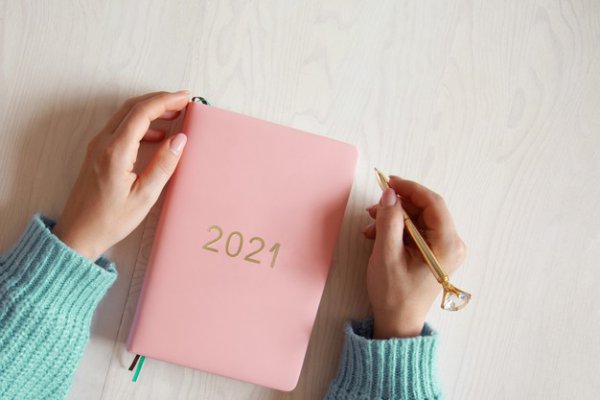 Pessoa com uma agenda rosa do ano de 2021