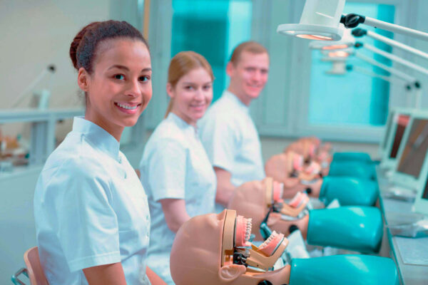 Estudantes praticando em laboratório com manequins odontológicos durante estágio em odontologia