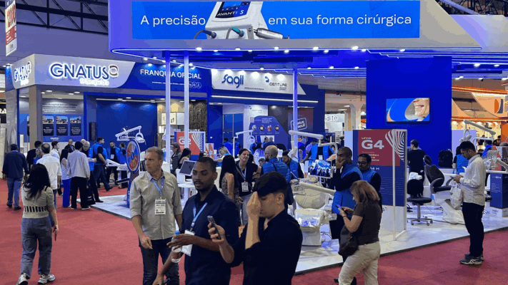 Estande da Gnatus no CIOSP, com demonstração de produtos e movimentação de visitantes em um grande evento de odontologia.