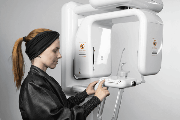 Profissional posicionando paciente em exame com raio x panorâmico em clínica odontológica