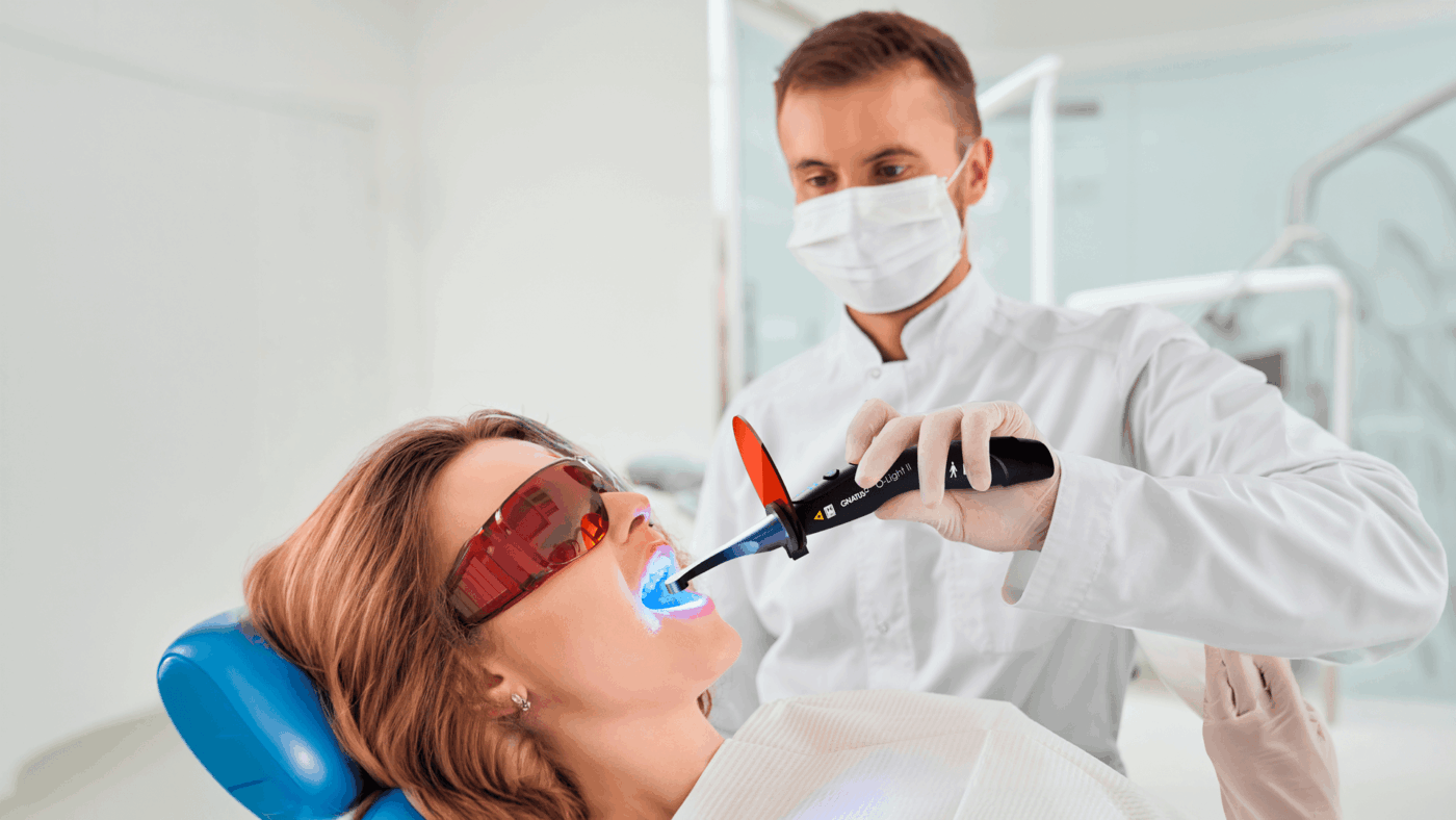 Uso de fotopolimerizador em procedimento odontológico para cura de resina durante atendimento clínico em consultório