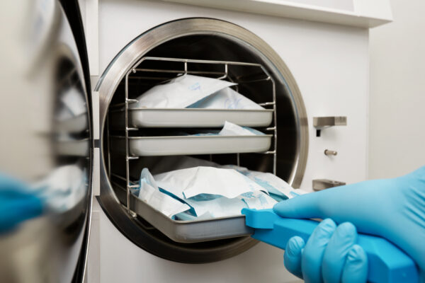 Biossegurança na odontologia com materiais esterilizados sendo retirados de autoclave em consultório odontológico