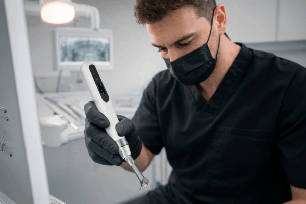 Dentista utilizando equipamento odontológico durante um tratamento endodôntico complexo em consultório.