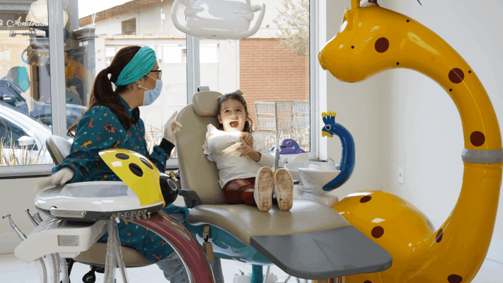 Odontopediatria em consultório infantil, com dentista atendendo criança em cadeira odontológica e ambiente lúdico para uma consulta mais acolhedora.