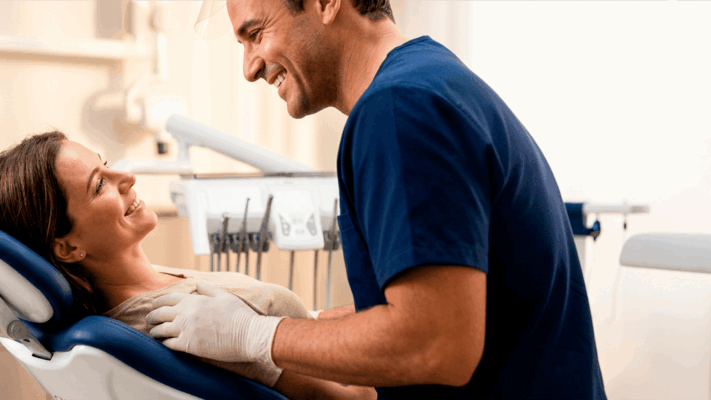 Dentista conversando com paciente em consultório odontológico, reforçando estratégias de atendimento para quem busca entender como atrair pacientes para consultório odontológico.