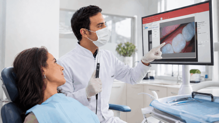 Dentista utiliza câmera intraoral para mostrar ao paciente imagens ampliadas dos dentes durante o tratamento odontológico.